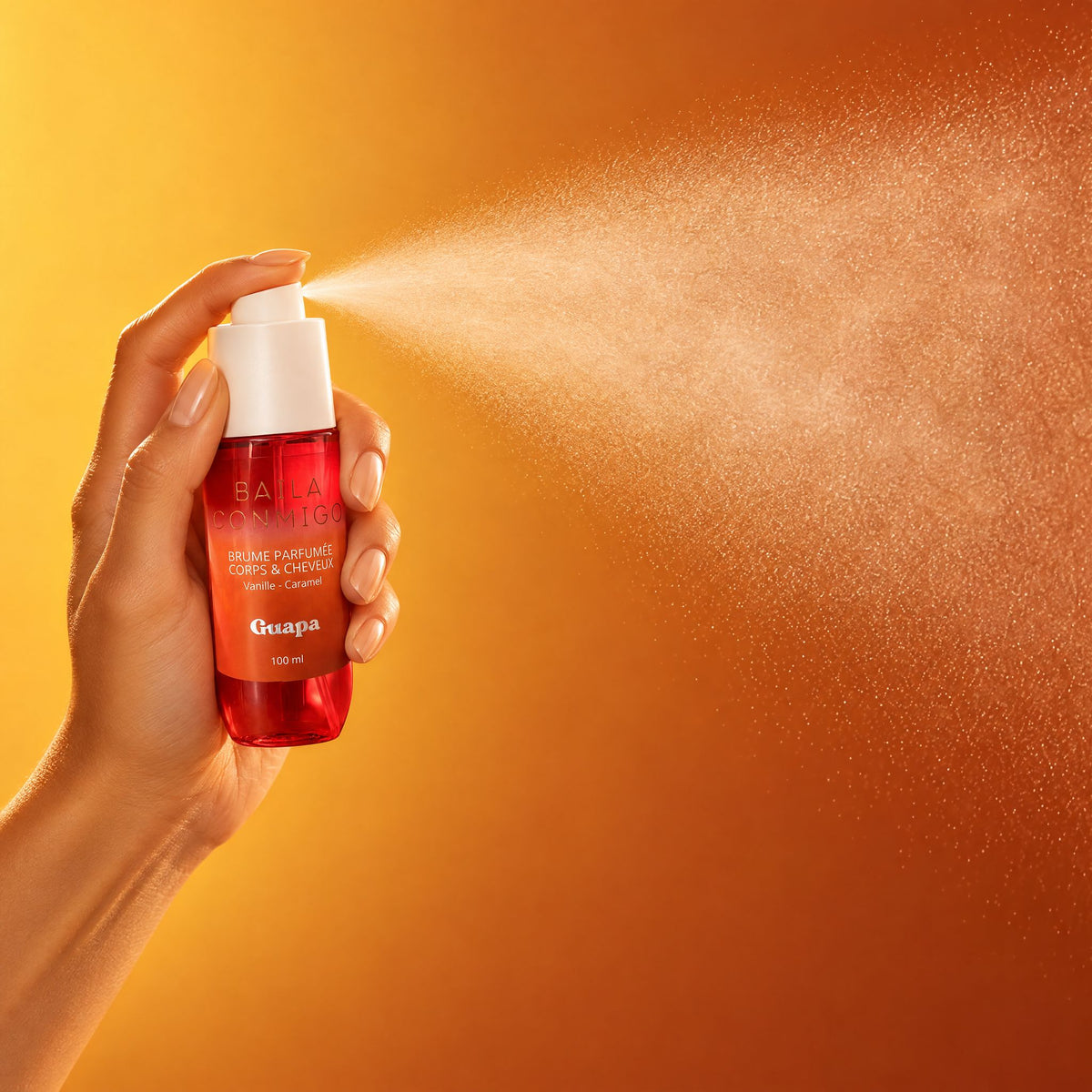 Brume parfumée corps et cheveux Vanille Caramel GUAPA vaporisée sur fond jaune doré et caramel