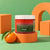 Gommage corps exfoliant doux Thé Vert Mandarine GUAPA 300 g sur blocs orange mandarine, fond vert
